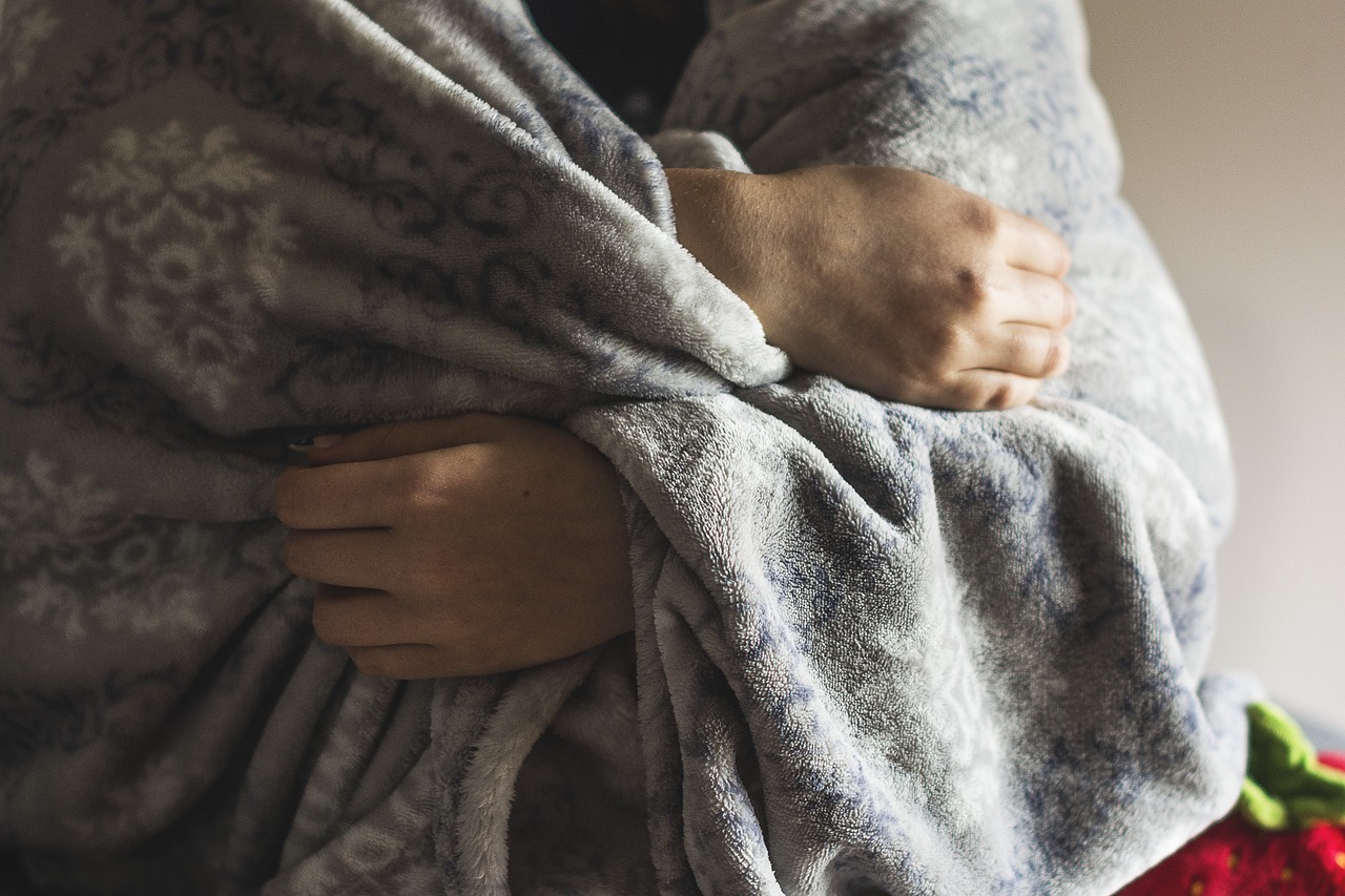 Mãos frias por causa do fenômeno de Raynaud, coberta com cobertor no inverno